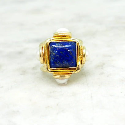 NIIKI NCR1406 LP La bague se distingue par son volume généreux et son architecture en cocktail ring. Le corps de la bague, conçu dans un métal doré au fini brossé et mat, offre une allure texturée presque sculpturale.