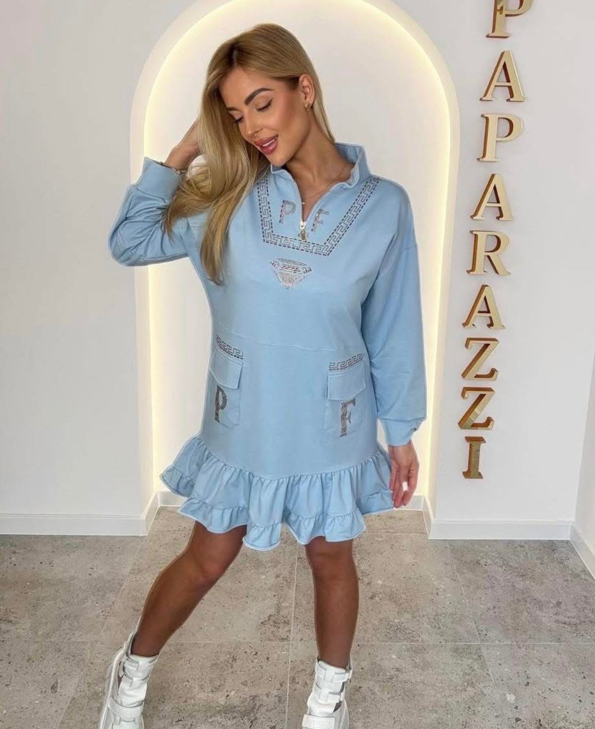 0080 robe-sweat bleu azur au style unique. Alliant confort et détails "couture" avec ses strass étincelants, son col zippé et ses volants romantiques, elle offre une allure urbaine et iconique pour toutes vos sorties.