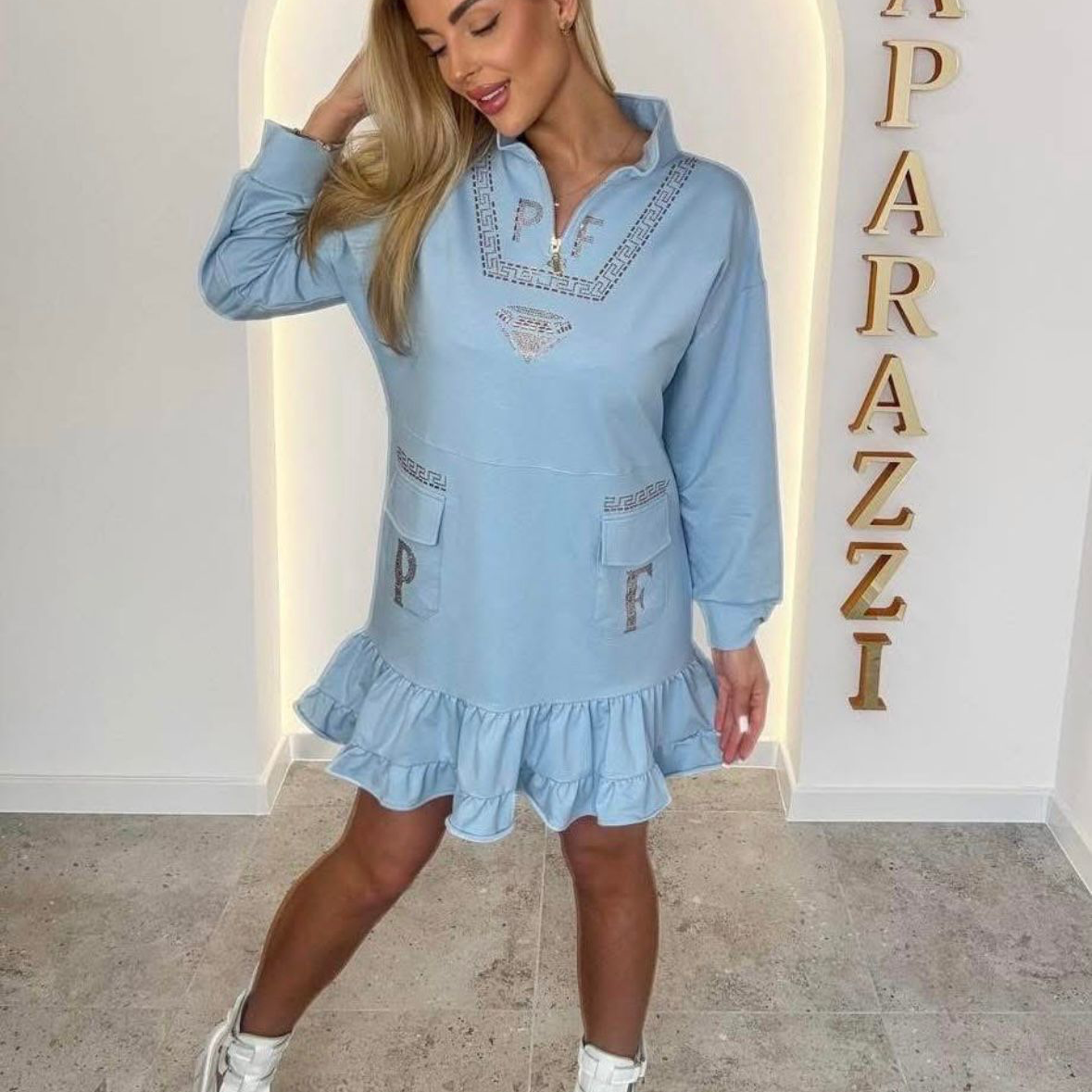0080 robe-sweat bleu azur au style unique. Alliant confort et détails "couture" avec ses strass étincelants, son col zippé et ses volants romantiques, elle offre une allure urbaine et iconique pour toutes vos sorties.