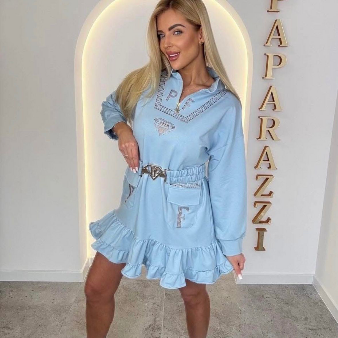 0080 robe-sweat bleu azur au style unique. Alliant confort et détails "couture" avec ses strass étincelants, son col zippé et ses volants romantiques, elle offre une allure urbaine et iconique pour toutes vos sorties.