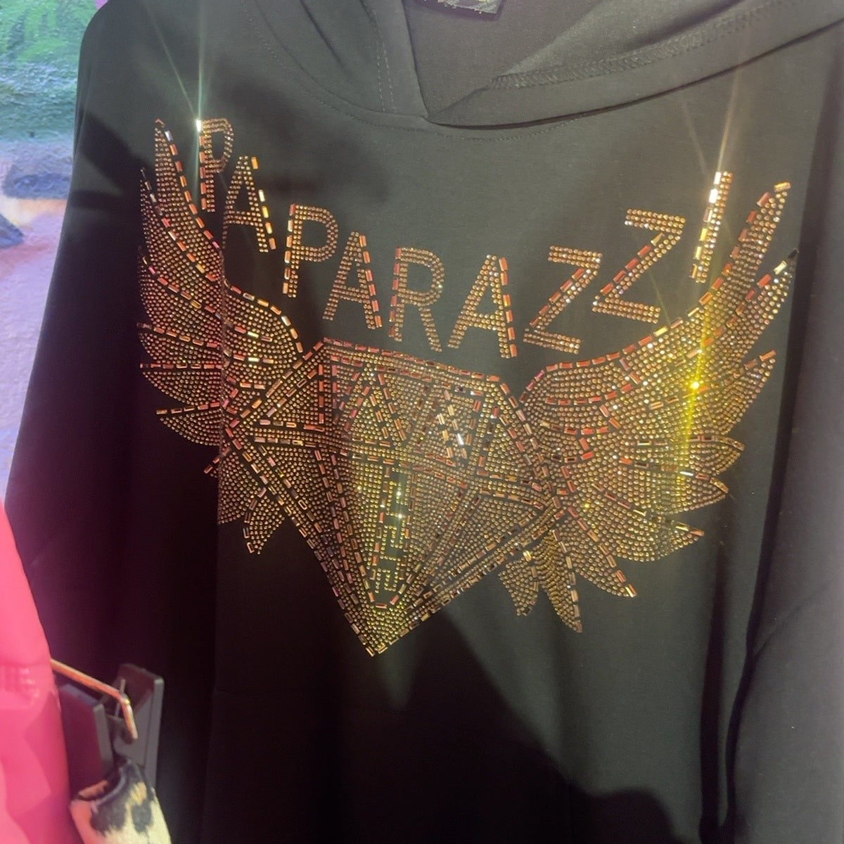 Gros plan du motif original Paparazzi en strass sur le sweat noir